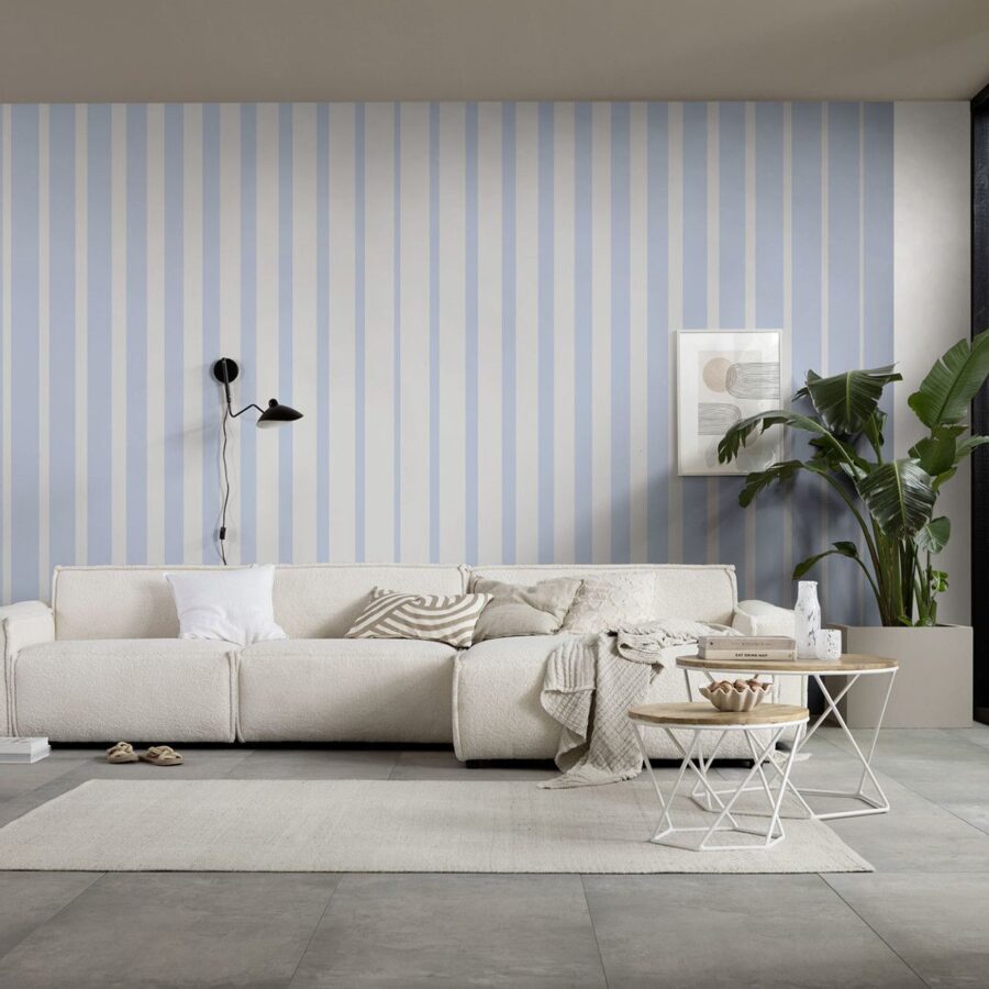 Lamello Longo Wandgestaltung mit blau-weißen Streifen hinter einer beige Couch; markante Pflanzen, dekorative Bilderrahmen, moderne Wohnraum-Atmosphäre