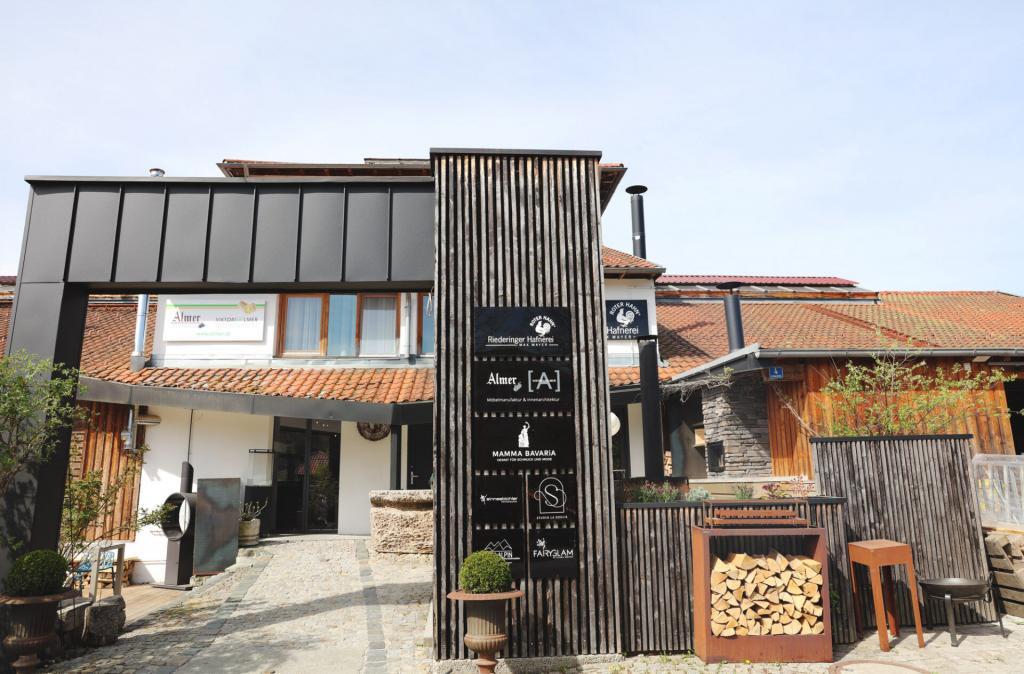Außenansicht der Riederinger Hafnerei Kooperation mit k’moor: schwarze vertikale Holzverkleidung, Firmenschilder und Eingangsbereich
