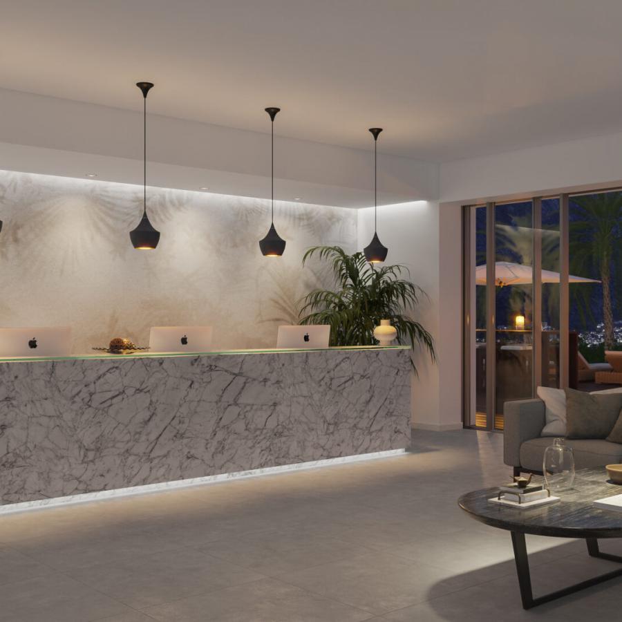 Interioraufnahme eines Empfangsbereichs mit Palmshades-Wanddesign in monochromen Naturnuancen, Marmorkanzle der Rezeption, feine Palmenblätter und Farne, Blick auf den Außenbereich mit Palmen und Terrassensitzgelegenheiten