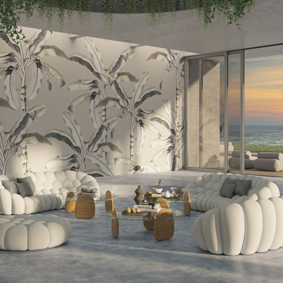 Studio Banana Grey Interiors: helle, weiße gepolsterte Sitzmöbel in einem Raum mit großem Blattmuster der Banana-Blatt-Wandgestaltung und Blick nach draußen auf eine Terrasse am Meer