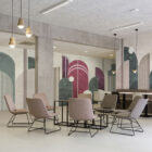 Loungebereich mit geometrischer Wandgestaltung in grün, pink und cremefarben, pastelrosa Sesseln mit schwarzen Metallrahmen; Colorante Archway Wandgestaltung von k'moor walldesign