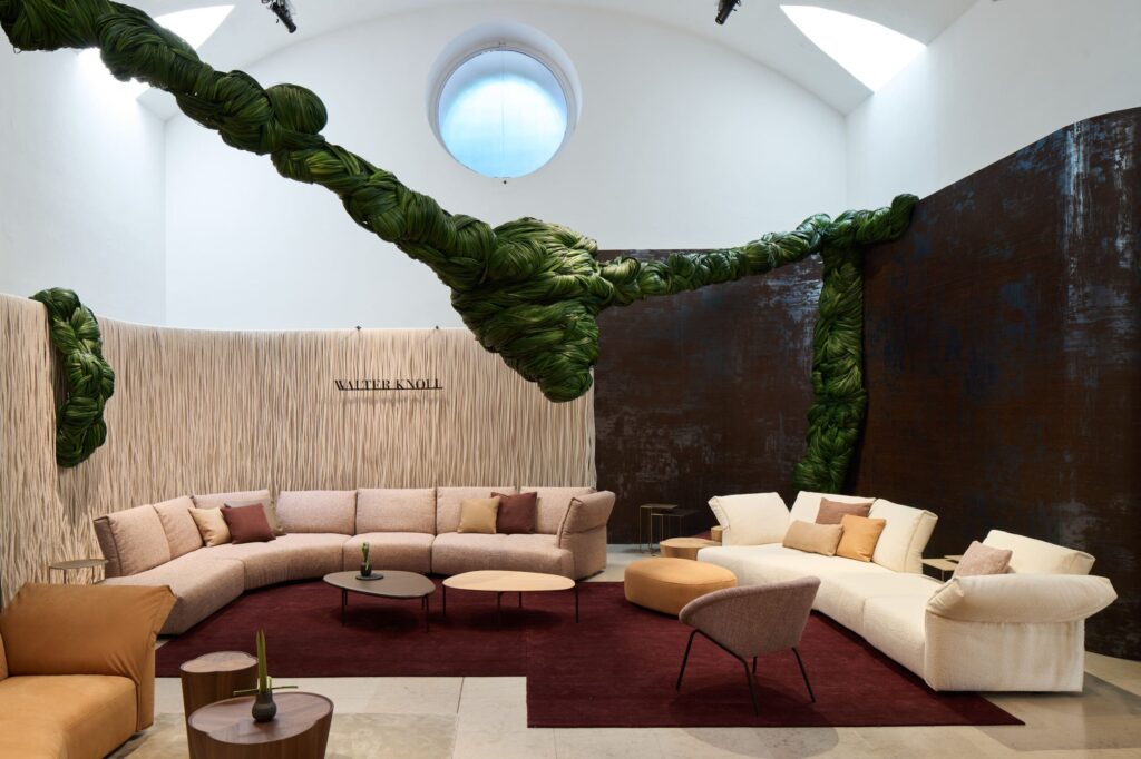 Im Raum von k’moor prägt ein grünes Flechtmotiv die Wandgestaltung bei Salone del Mobile, mit Schriftzug Walter Knoll und brauner Fläche.
