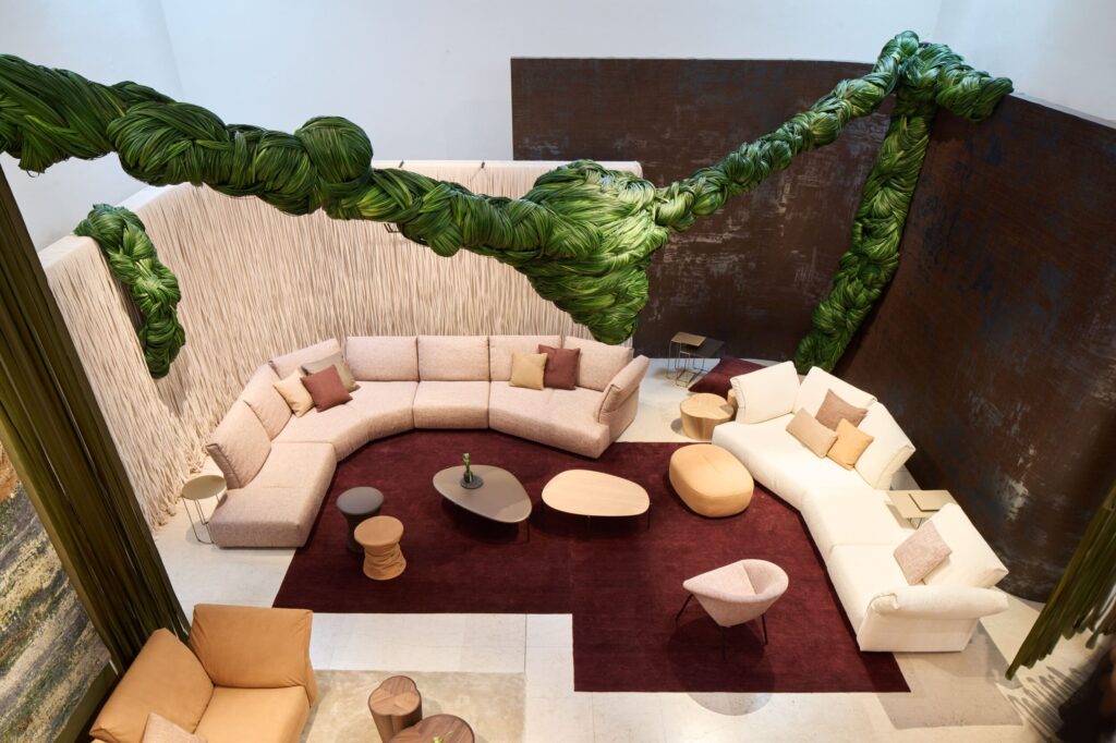 Beiger Lounge-Bereich mit weinroten Elementen und einem markanten grünen Pflanzenmotiv an der Wand, umgesetzt als subtile Bühne für Walter Knoll.