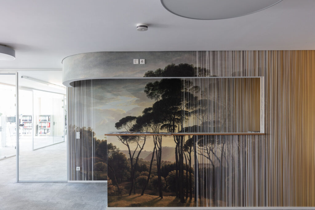 A curved office wall by Walter Knoll x k’moor combines a landscape mural with fine vertical lines and warm wood tones.