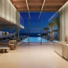 Das k'moor Wanddesign Ripple zeigt einen modernen Innenraum mit Blick auf Pool, Palmen und Meer bei Abendlicht.